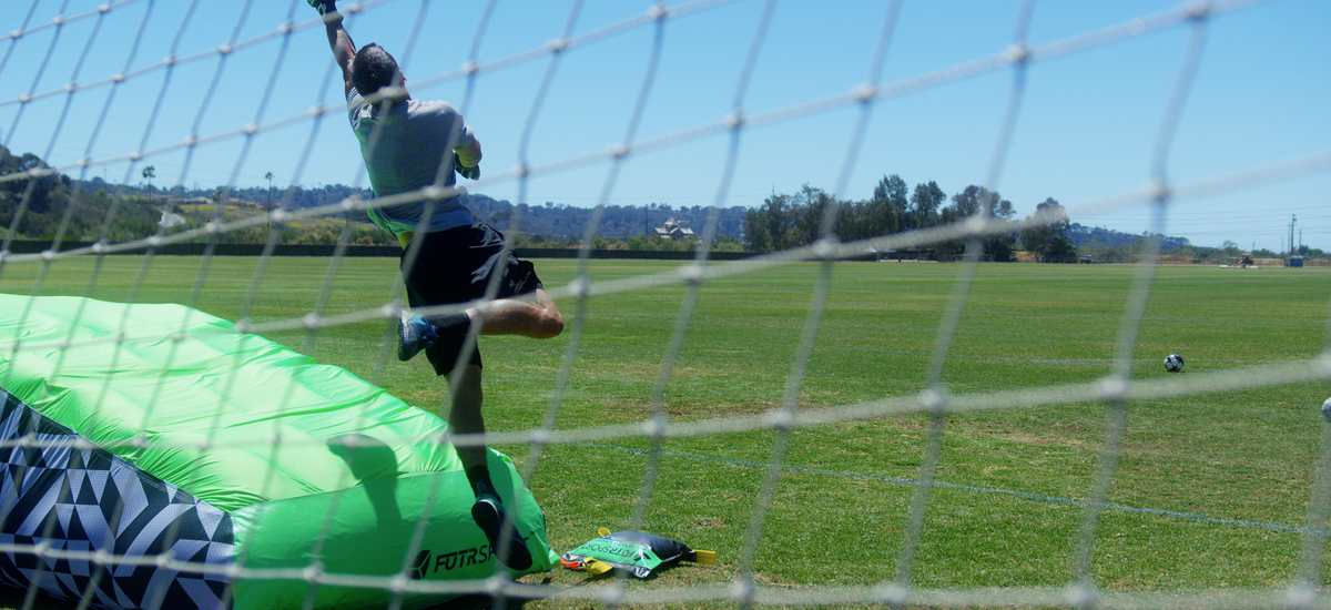 Goalkeeper reaching for a high ball beside the PENTA airbag